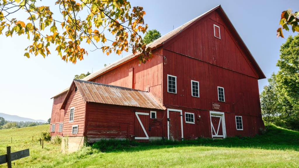 Historic red barn in Stowe, Vermont surrounded by green fields and mountain views in the countryside