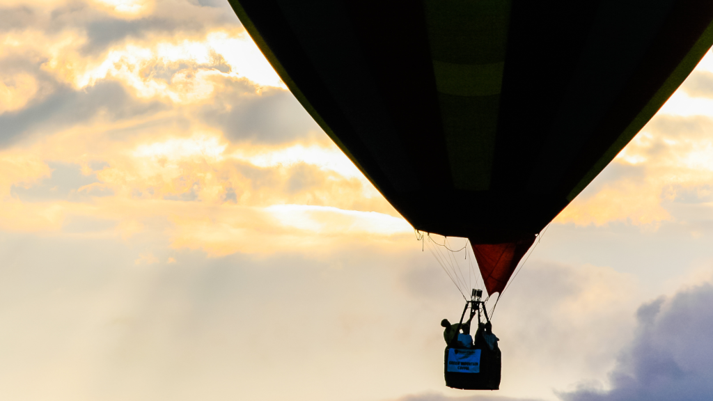 Colorful hot air balloons rising over the mountains during the Stowe Balloon Festival in Stowe, Vermont on a clear summer day