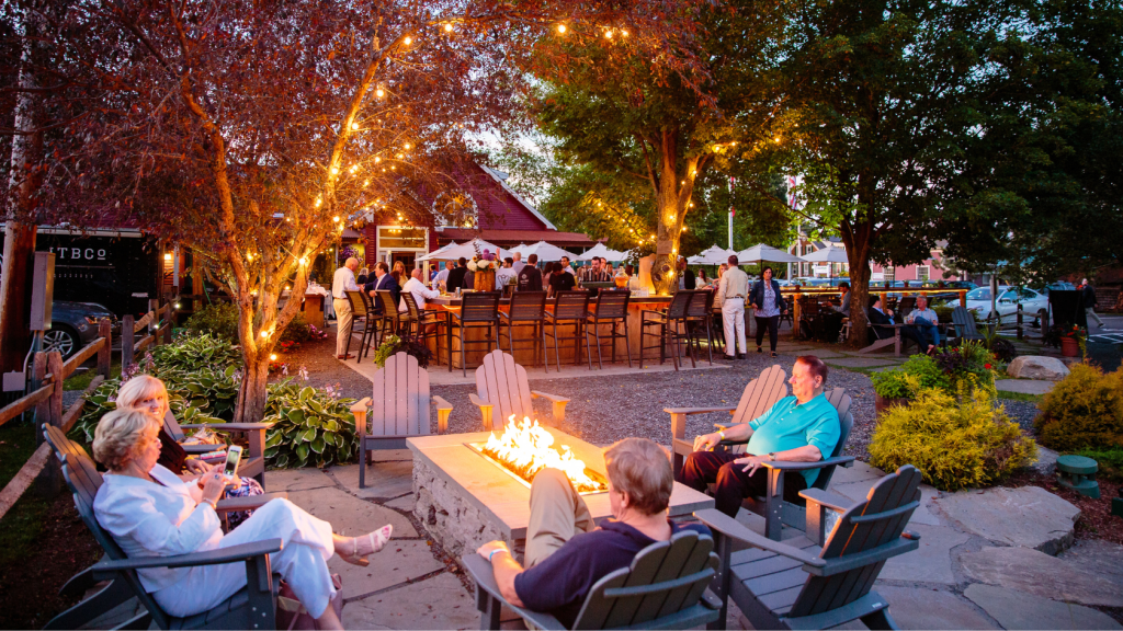People enjoying a lively night out at a restaurant in Stowe, Vermont with outdoor dining, lights, and a vibrant evening atmosphere
